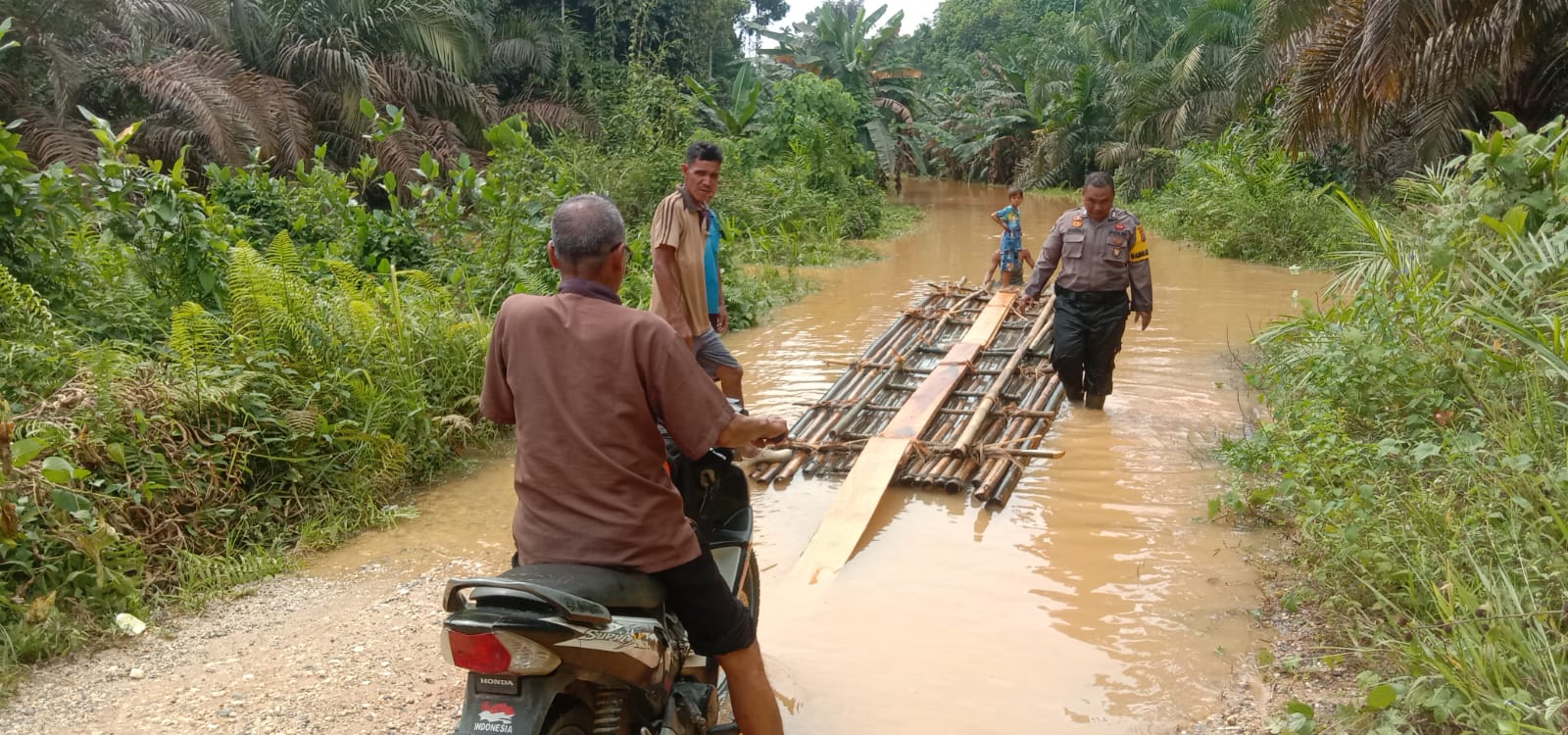 Ruas Jalan Desa Usul - Siambul Terendam Banjir, Bripka Habibi Berjibaku Sebrangkan Warga